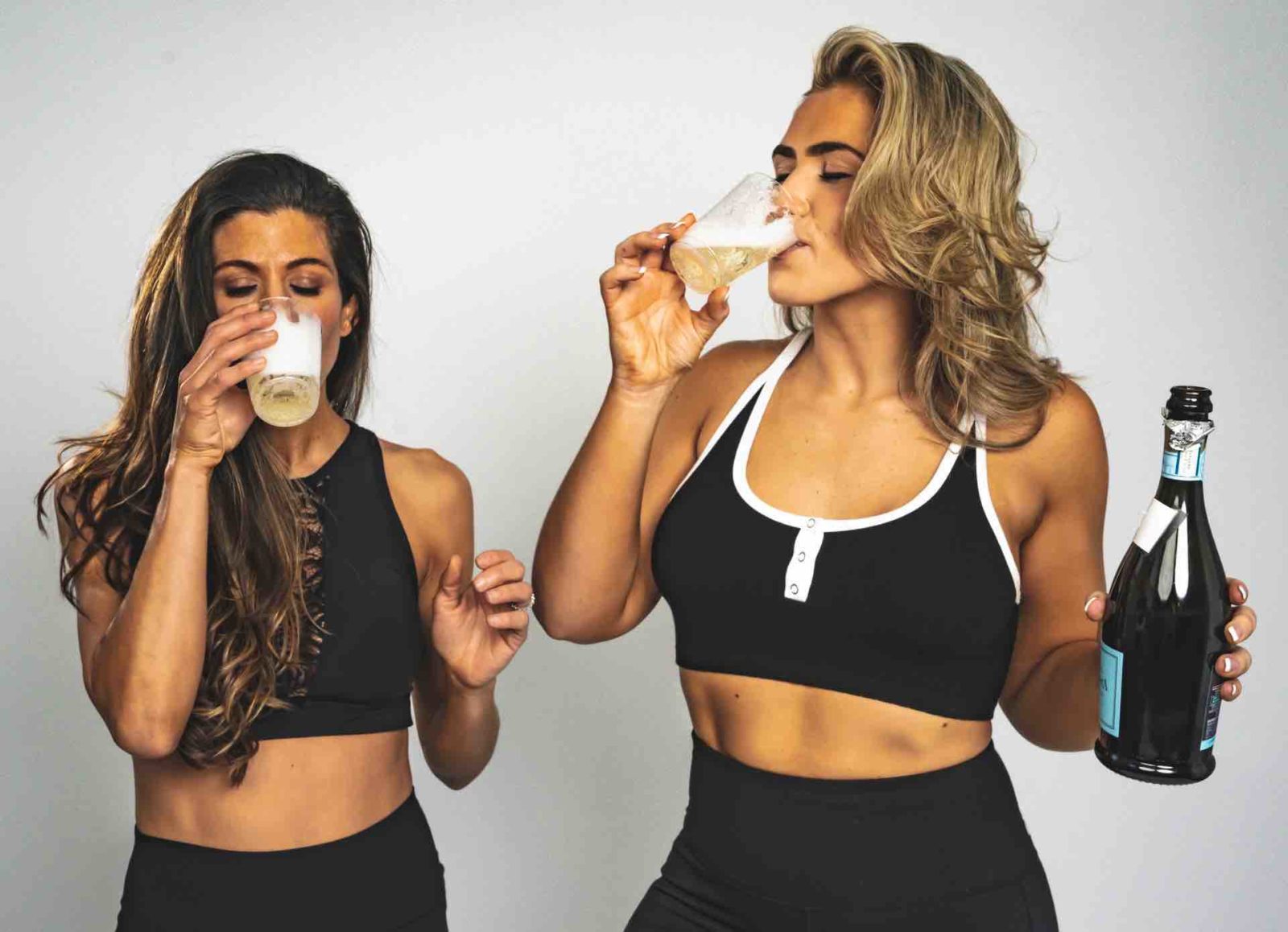 Two women drinking wine after a workout